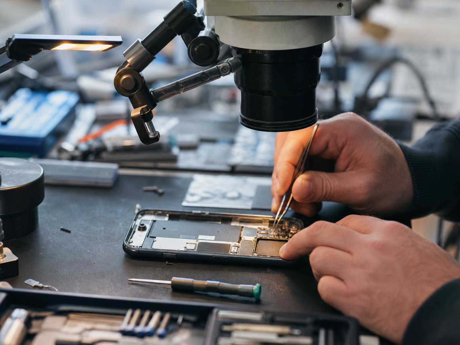 Technician microsoldering a smartphone logic board at the Dundee workshop bench